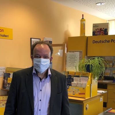 Bürgermeister Arnim Roß mit Maske vor der Postagentur Oberkaufungen.