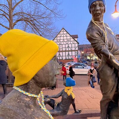 Bild vergr&ouml;&szlig;ern: Jugendliche aus dem Bereich »Kinder- und Jugendbeteiligung« der Gemeinde statteten die Figuren der Skulptur »Knottenfresser&Bohnenbiedel« mit Mützen und Schals in den ukrainischen Nationalfarben aus.