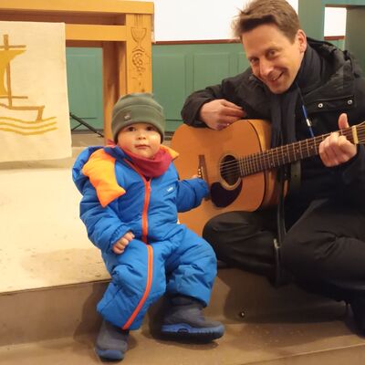 Bild vergr&ouml;&szlig;ern: Lasse (2) spielte mit Pfarrer Synofzik auf der Gitarre ein "Quatschlied"