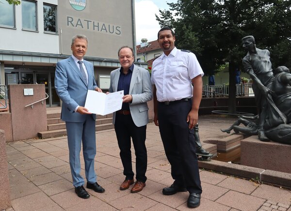 Bild vergr&ouml;&szlig;ern: Bürgermeister Arnim Roß und Gemeindebrandinspektor Brian Edokpolor nahmen den Förderbescheid von Innenstaatssekretär Martin Rößler entgegen.