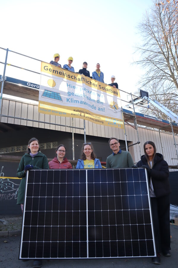 Eine neue Photovoltaikanlage wurde im Rahmen einer Mitmachbaustelle auf dem Dach des Nebengebäudes der Kita Eulennest installiert. Vorne im Bild: (v.l.) Lisa Haubner (Klimaschutzmanagerin der Kunigundengemeinde Kaufungen), Sarah Link (cdw Stiftung), Anna Schlling (Solocal Energy), Thomas Flügge (cdw Stiftung) und Teilnehmerin Larissa Zekiri. Oben im Bild weitere Teilnehmende der Mitmach-Baustelle. 