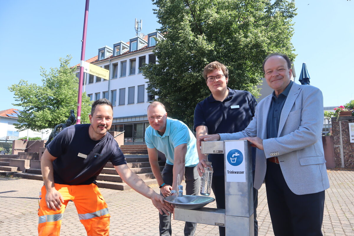 Eine von drei Trinkwasserstationen steht in Oberkaufungen vor dem Rathaus: (v.r.) Bürgermeister Arnim Roß, Julius Krause (Klimaanpassungsmangager), Stefan Müller (Fachbereichsleiter Tiefbau, Stadt- und Landschaftsplanung, Infrastruktur) und Timo Windemuth (Gemeindebetriebe Kaufungen) stellten das neue Angebot vor. 