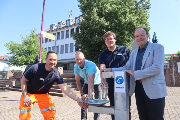 Eine von drei Trinkwasserstationen steht in Oberkaufungen vor dem Rathaus: (v.r.) Bürgermeister Arnim Roß, Julius Krause (Klimaanpassungsmangager), Stefan Müller (Fachbereichsleiter Tiefbau, Stadt- und Landschaftsplanung, Infrastruktur) und Timo Windemuth (Gemeindebetriebe Kaufungen) stellten das neue Angebot vor. 