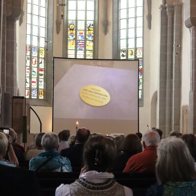 Bild vergr&ouml;&szlig;ern: Im Innenraum der Stiftskirche wird auf einer Leinwand vor Publikum ein Film gezeigt.